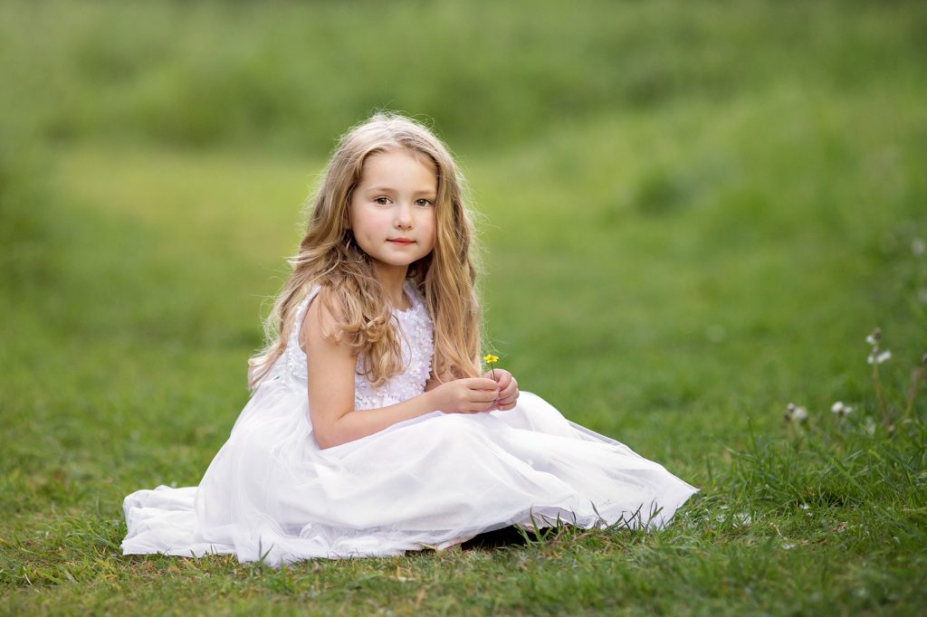 girl sitting in field with yellow flower photographed in a Kent park