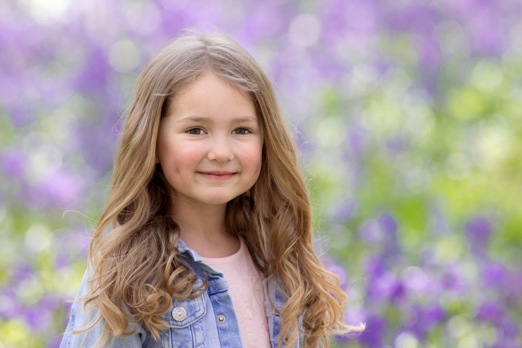 close up of little girl with curly hair during a bluebell photoshoot in Chatham