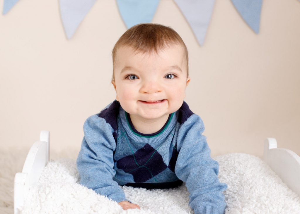 boy smiling in a blue jumper during his 1st birthday photoshoot at Chatham studio