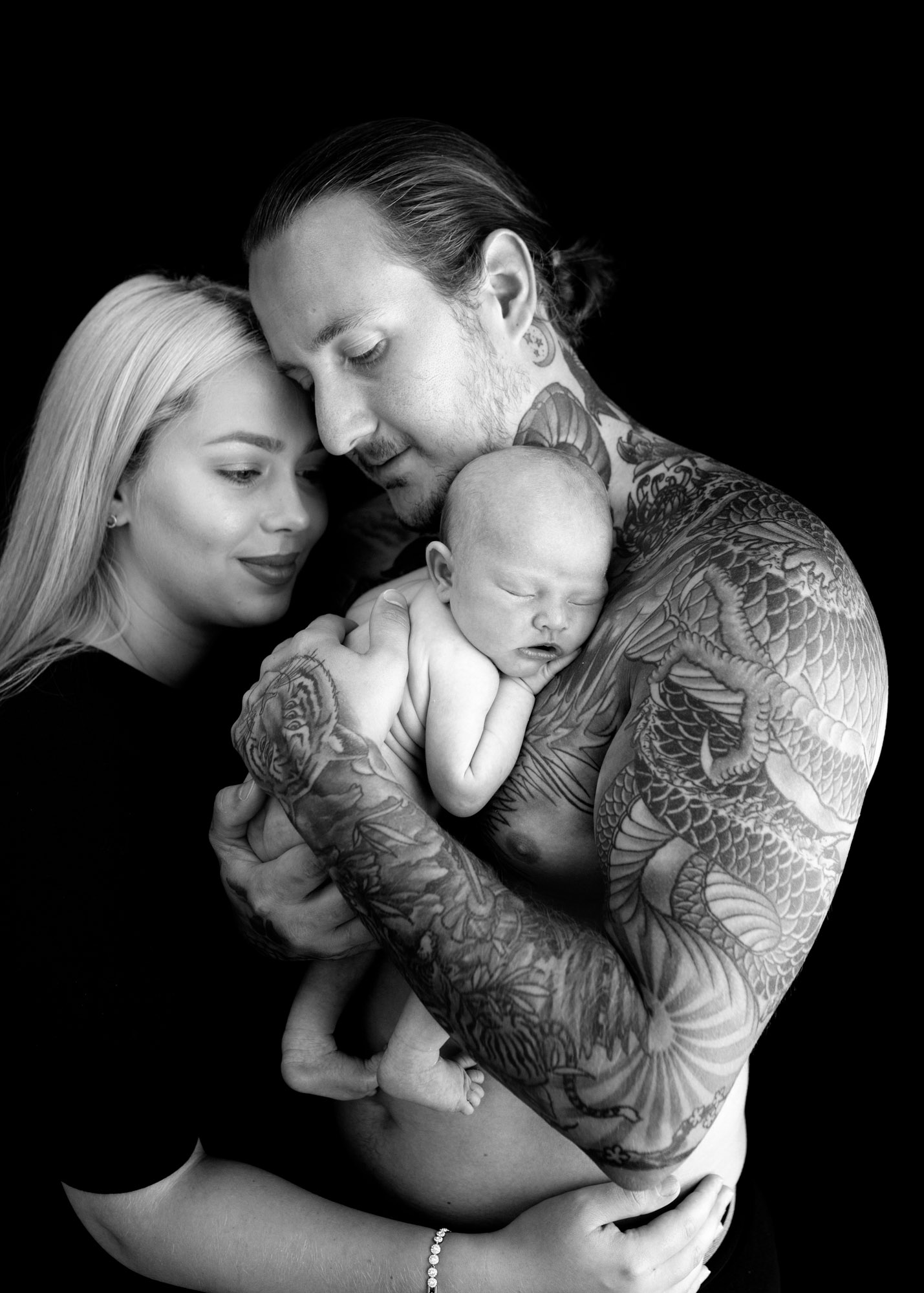 mum, dad and newborn girl laying on dads arm of tattoos during Chatham photoshoot