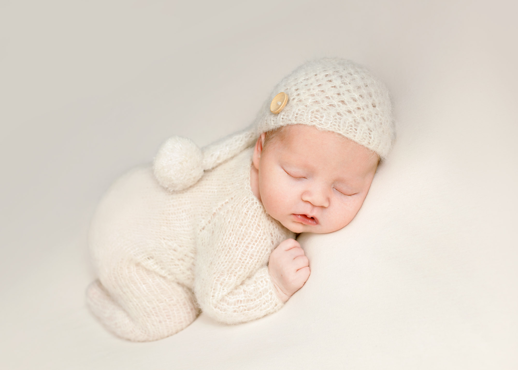 baby with cream knitted hat and romper