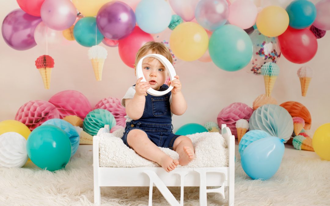 boy poking head through wooden letter surrounding by balloons on a birthday photoshoot in Chatham