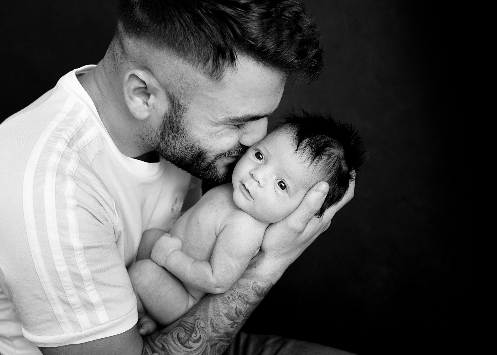 dad kissing newborn baby photographed in Kent