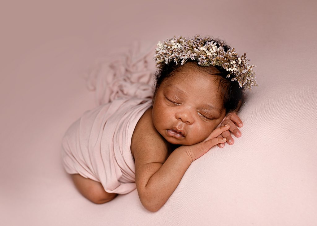 newborn baby girl photographed on pink in a studio in Kent