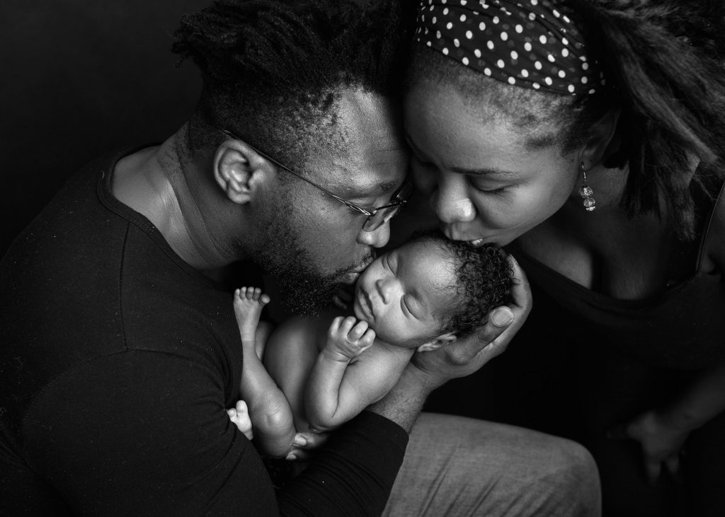 parents kissing newborn baby during a photoshoot in Kent