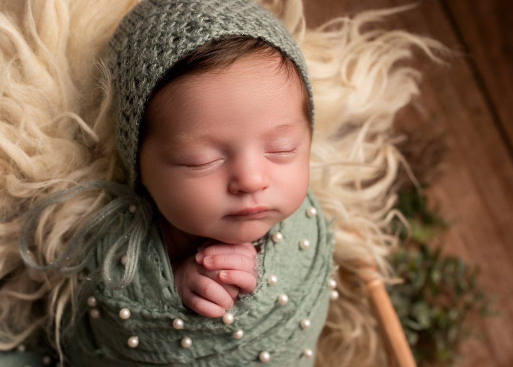 newborn girl wearing a green bonnet photographed in Chatham