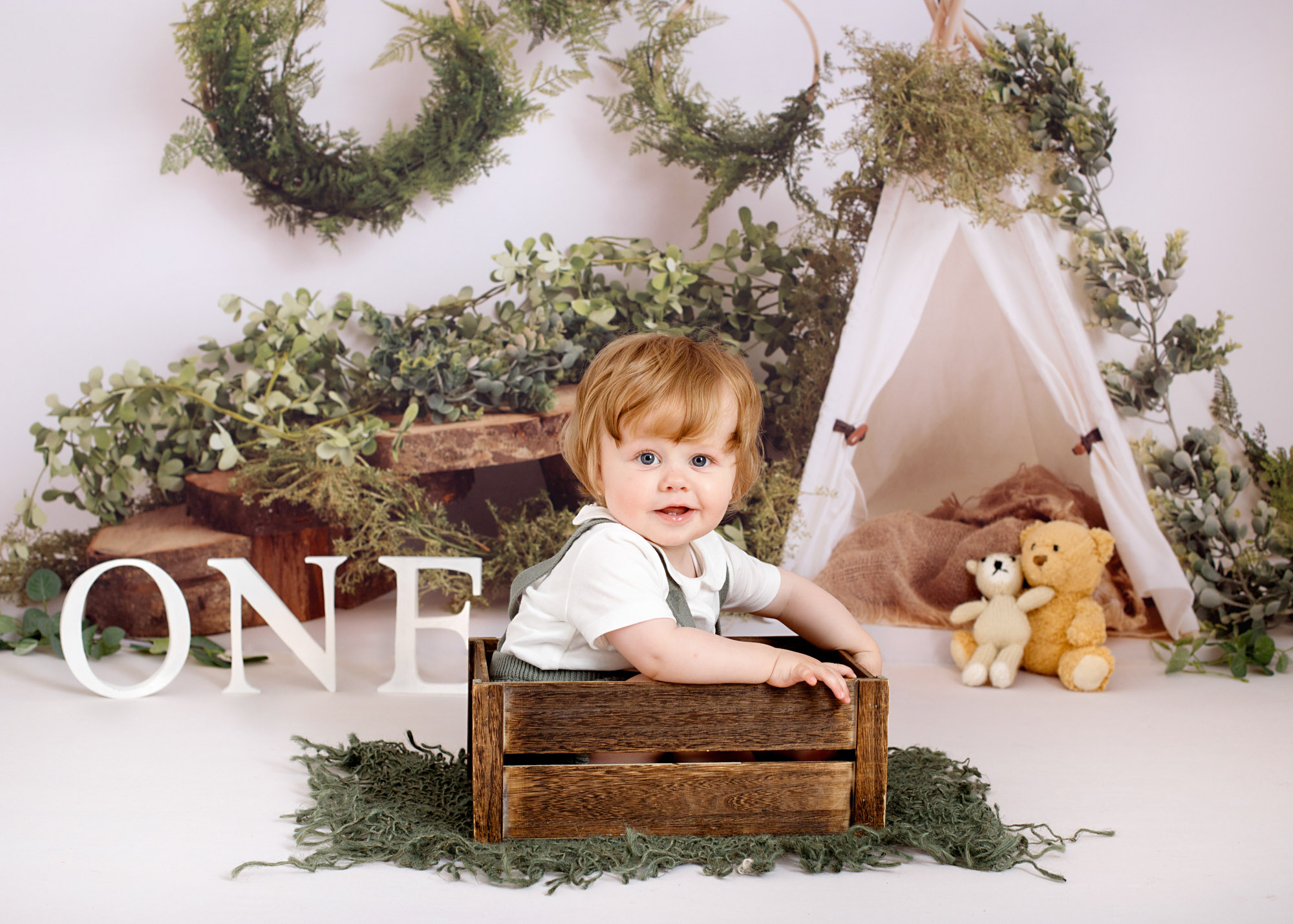 baby sitting in wooden box during a 1st birthday photoshoot in Chatham