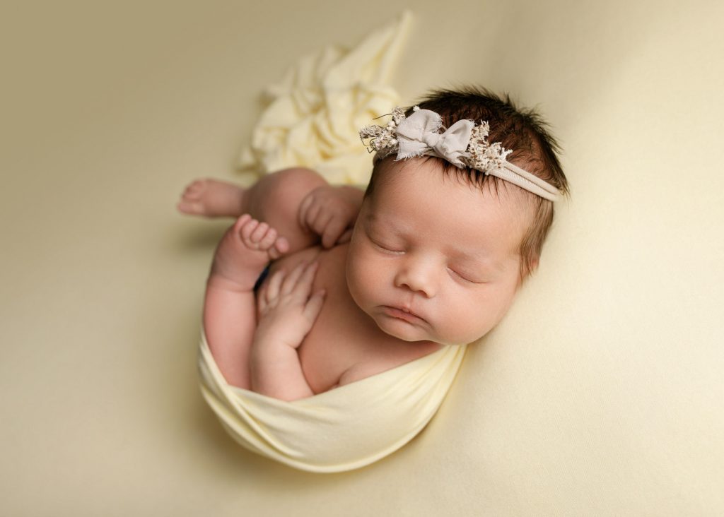 Baby girl wrapped in yellow during a newborn photoshoot in Chatham