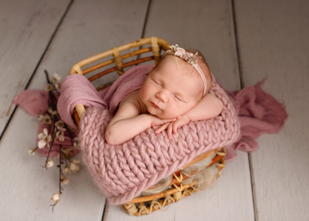 baby girl laying in a basket during a photoshoot in Chatham