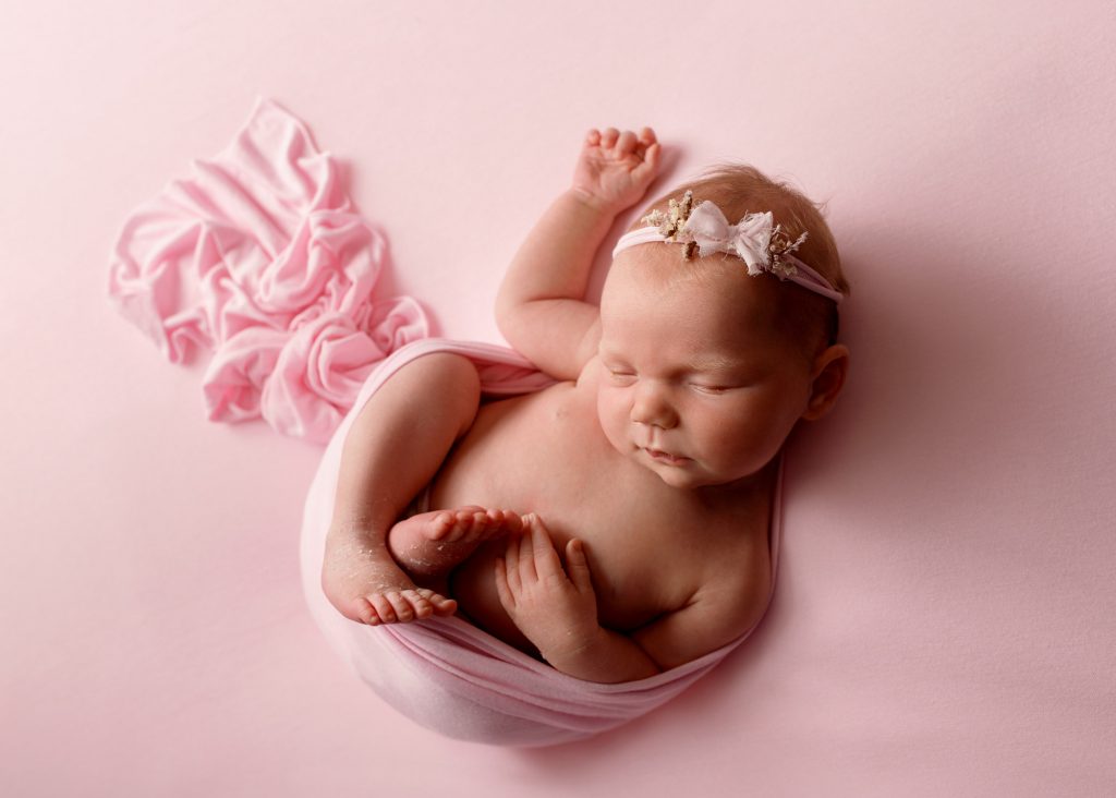 newborn baby girl asleep on pink photographed in Kent