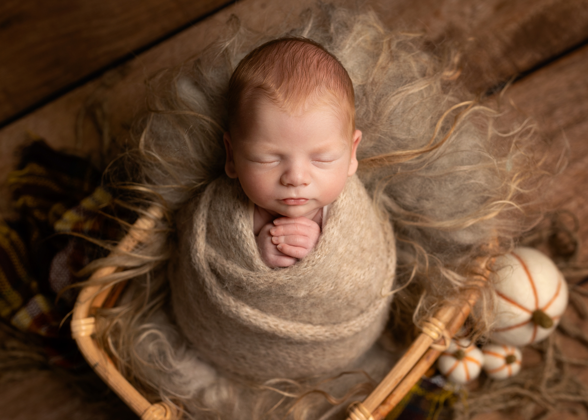baby swaddled in brown blanket laying in a basket during a photoshoot in Kent