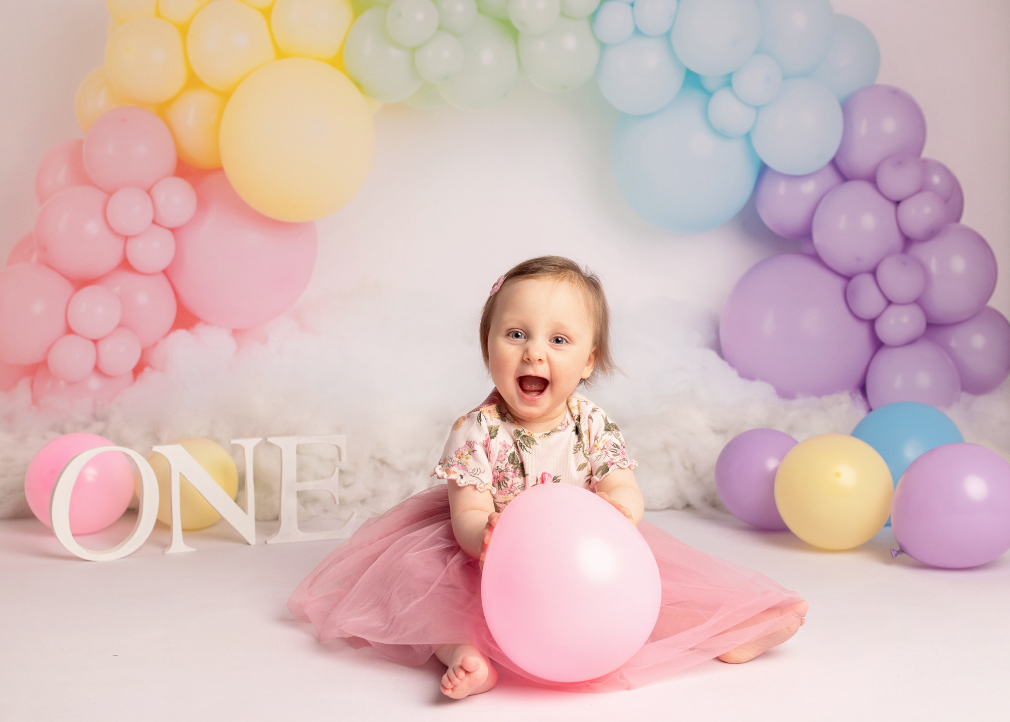 Baby girl holding a pink balloon on her first birthday photoshoot in Kent