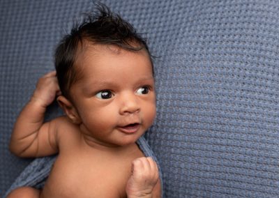 Baby boy with big eyes looking out at his mum during a newborn photoshoot in Kent