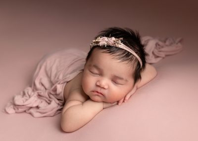 Newborn baby girl with pink blanket and pink headband during a photoshoot in Kent