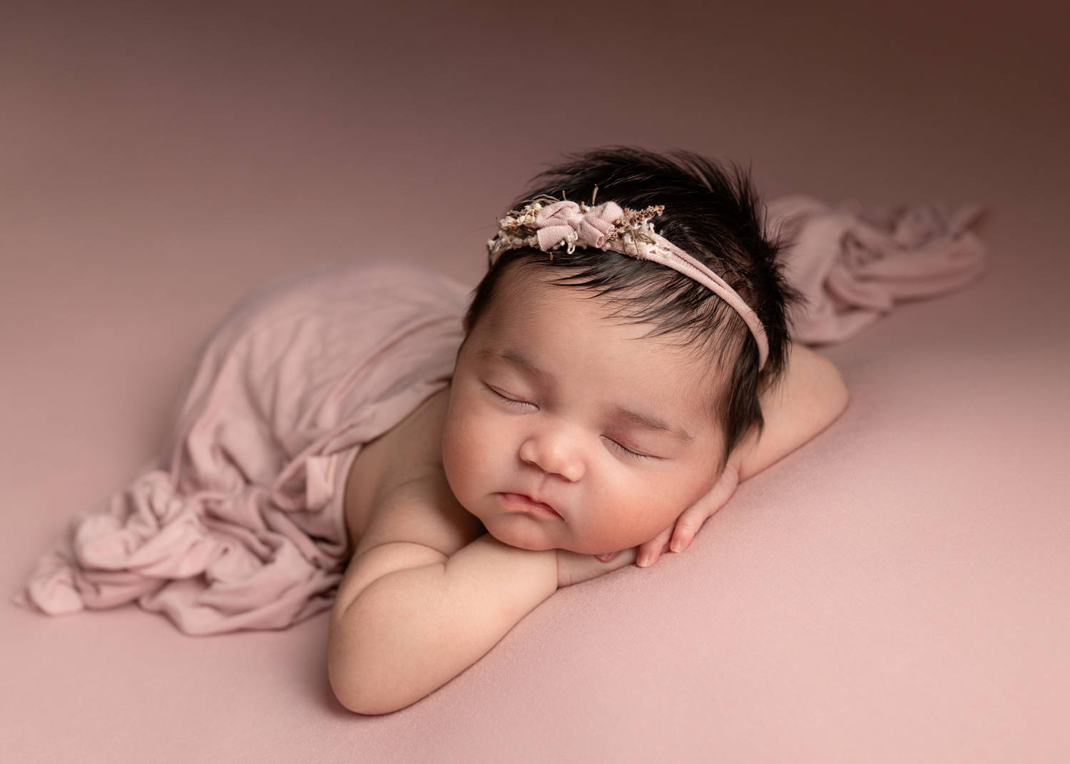 Newborn baby girl with pink blanket and pink headband during a photoshoot in Kent