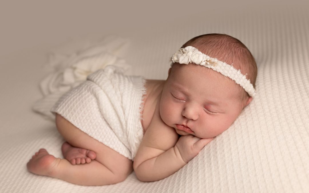 newborn baby girl curled up on a white blanket during a newborn photoshoot in Kent