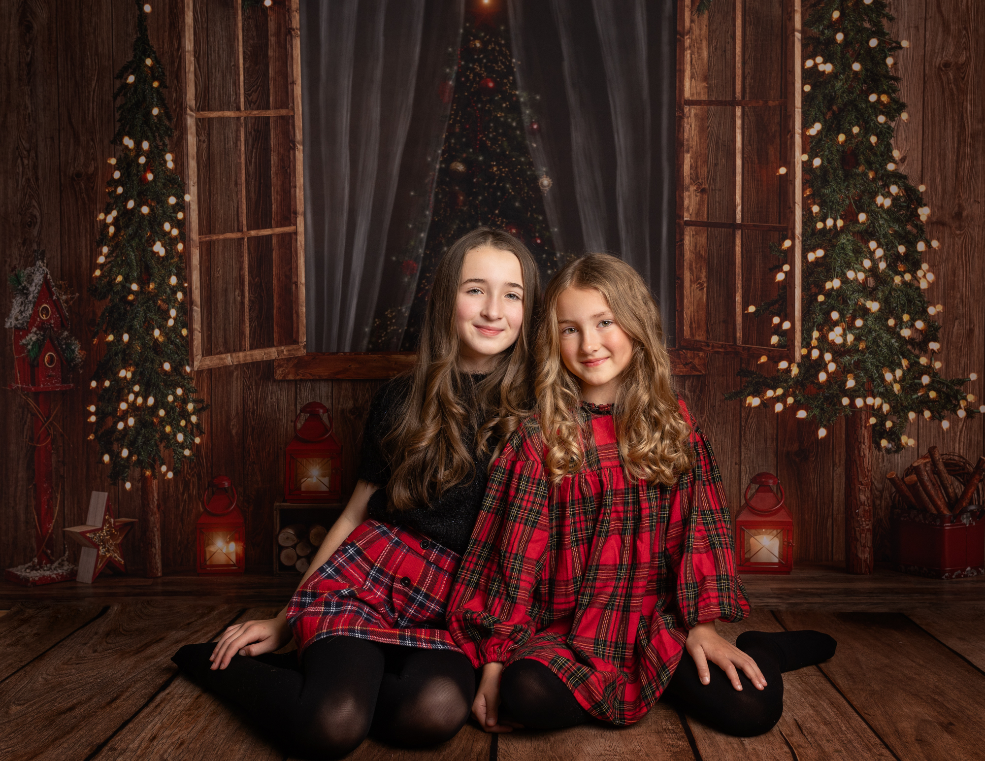 Sisters wearing tartan dresses sat by Christmas tree for a photoshoot in Kent