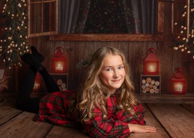 Girl dressed in Tartan laying on wooden floor being photographed during a Christmas mini shoot on Kent