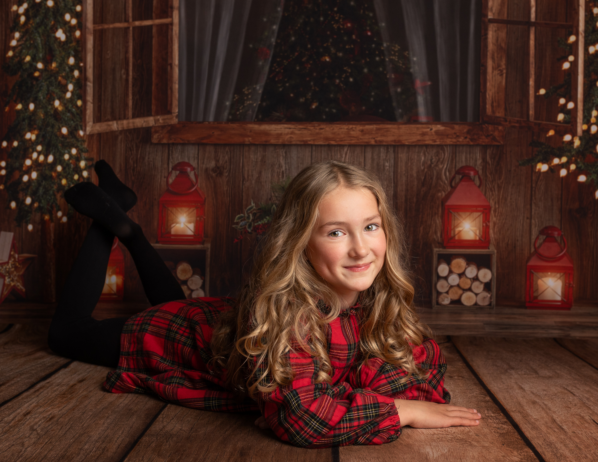 Girl dressed in Tartan laying on wooden floor being photographed during a Christmas mini shoot on Kent